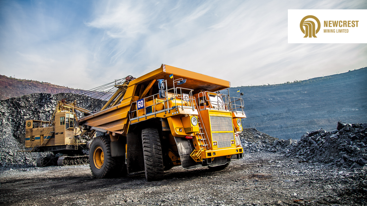 Large yellow mining trucks in a quarry with Newcrest Mining Unlimited logo.